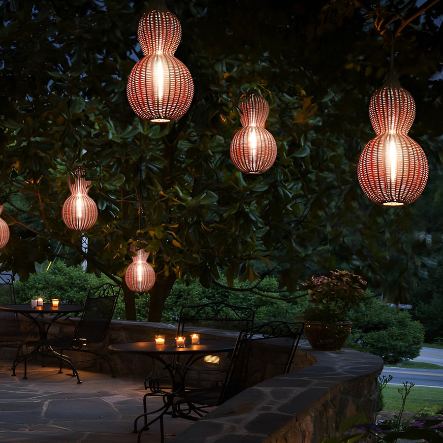 Modern rattan pendant light cluster hanging from a large tree, forming a cozy atmosphere over an outdoor bar area.