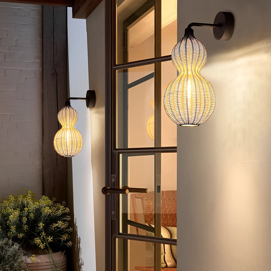 Modern rattan pendant light used as an outdoor wall-mounted fixture beside a doorway, creating a welcoming glow.