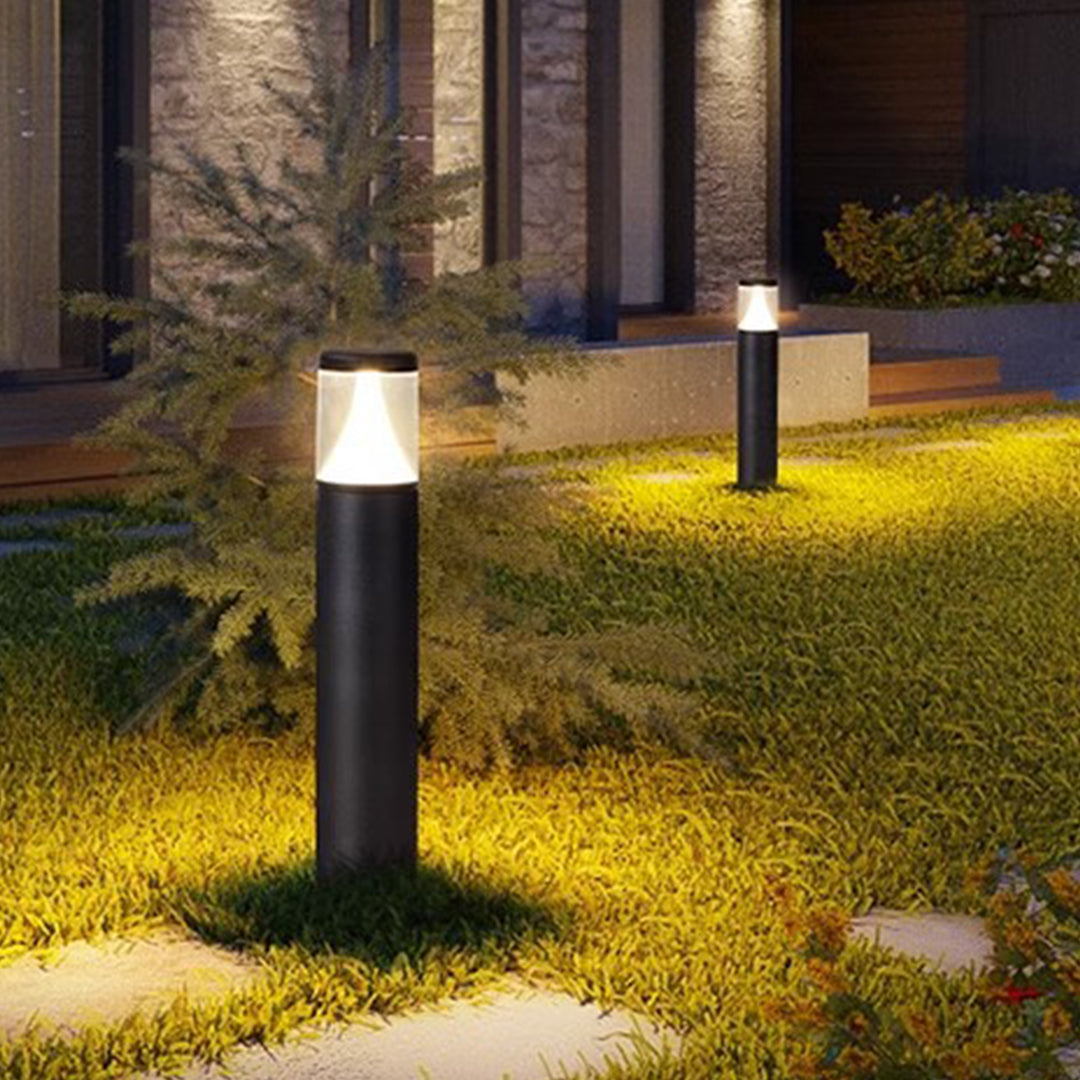 Modern residential exterior featuring sleek bollard lights illuminating lawn and walkway areas
