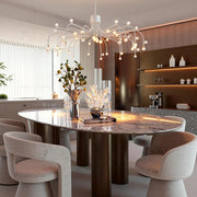 Modern retro chandelier illuminating luxury dining area with marble table and velvet seating in sophisticated interior