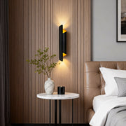 Modern scroll wall sconce in black and gold, mounted beside a bed for stylish and functional bedroom lighting.