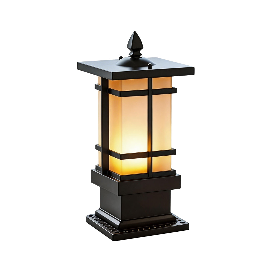 A short black garden bollard lighting fixture with a square base and warm frosted glass panels.