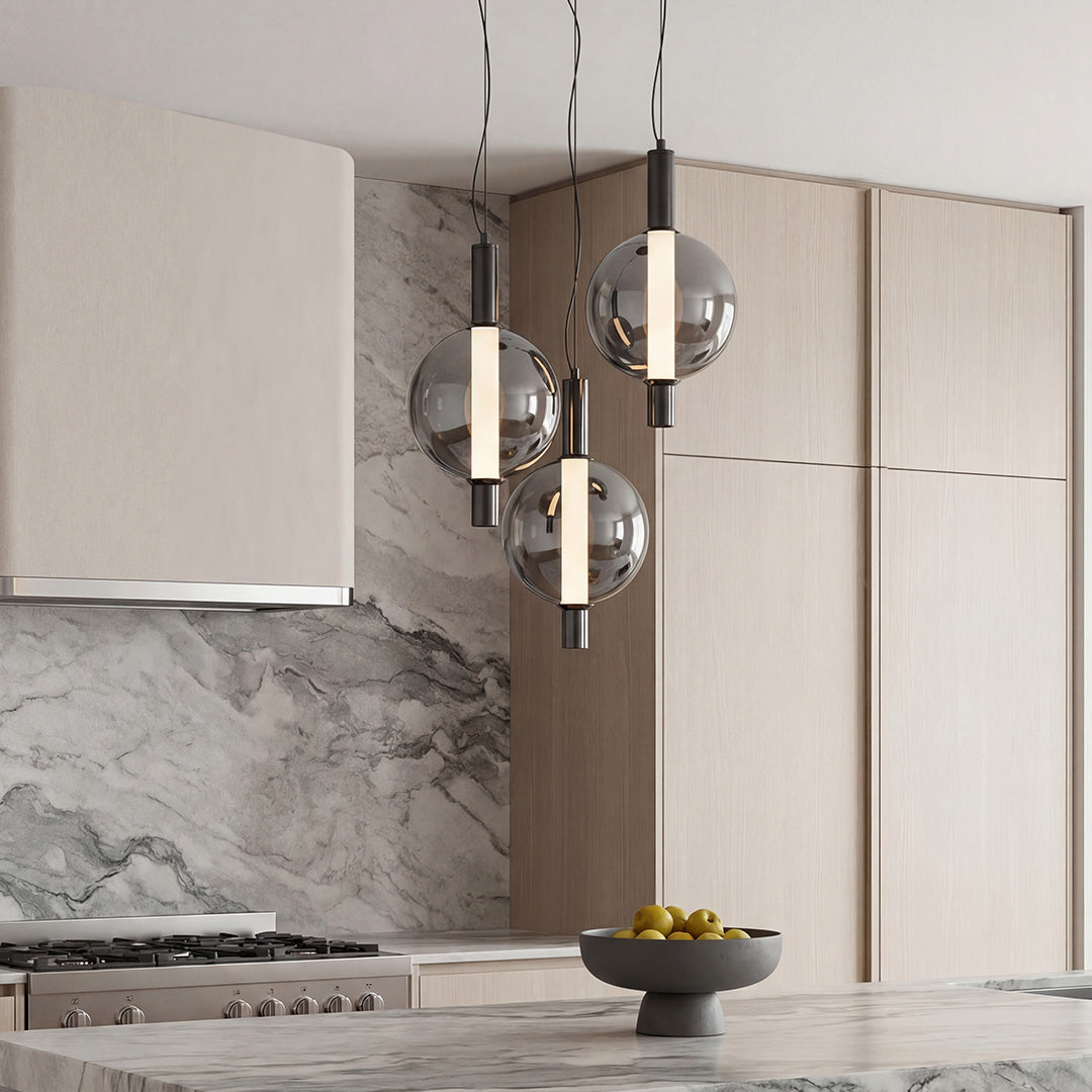 Sleek modern silver pendant light trio with smoked glass globes above a luxury marble kitchen.