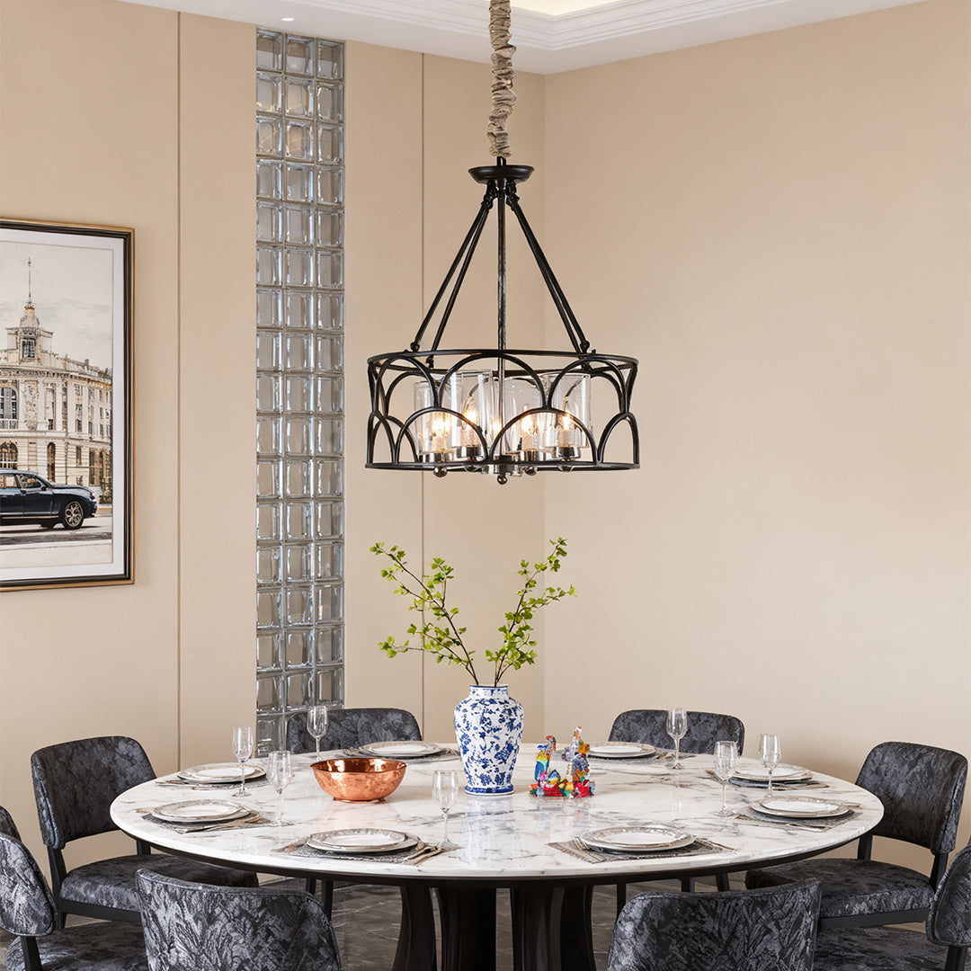 A modern six-light chandelier with black caged frame and internal crystal drops, illuminating a round marble dining table.