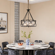 A modern six-light chandelier with black caged frame and internal crystal drops, illuminating a round marble dining table.