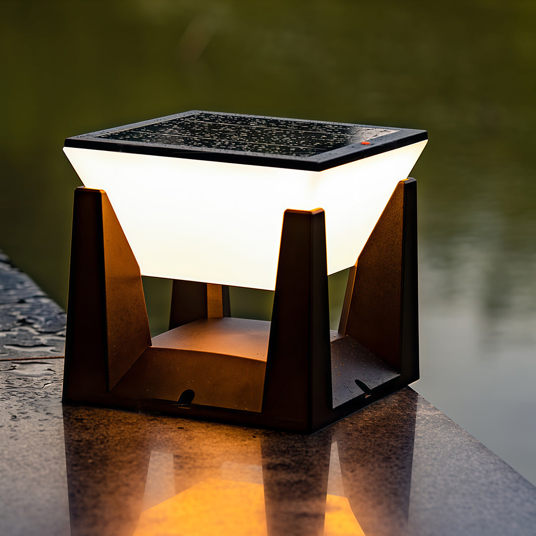 Modern solar bollard light casting a warm, glowing reflection on a wet stone surface at dusk.
