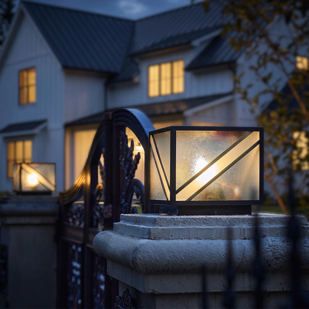 Modern solar pillar light with textured glass on stone gate column beside home