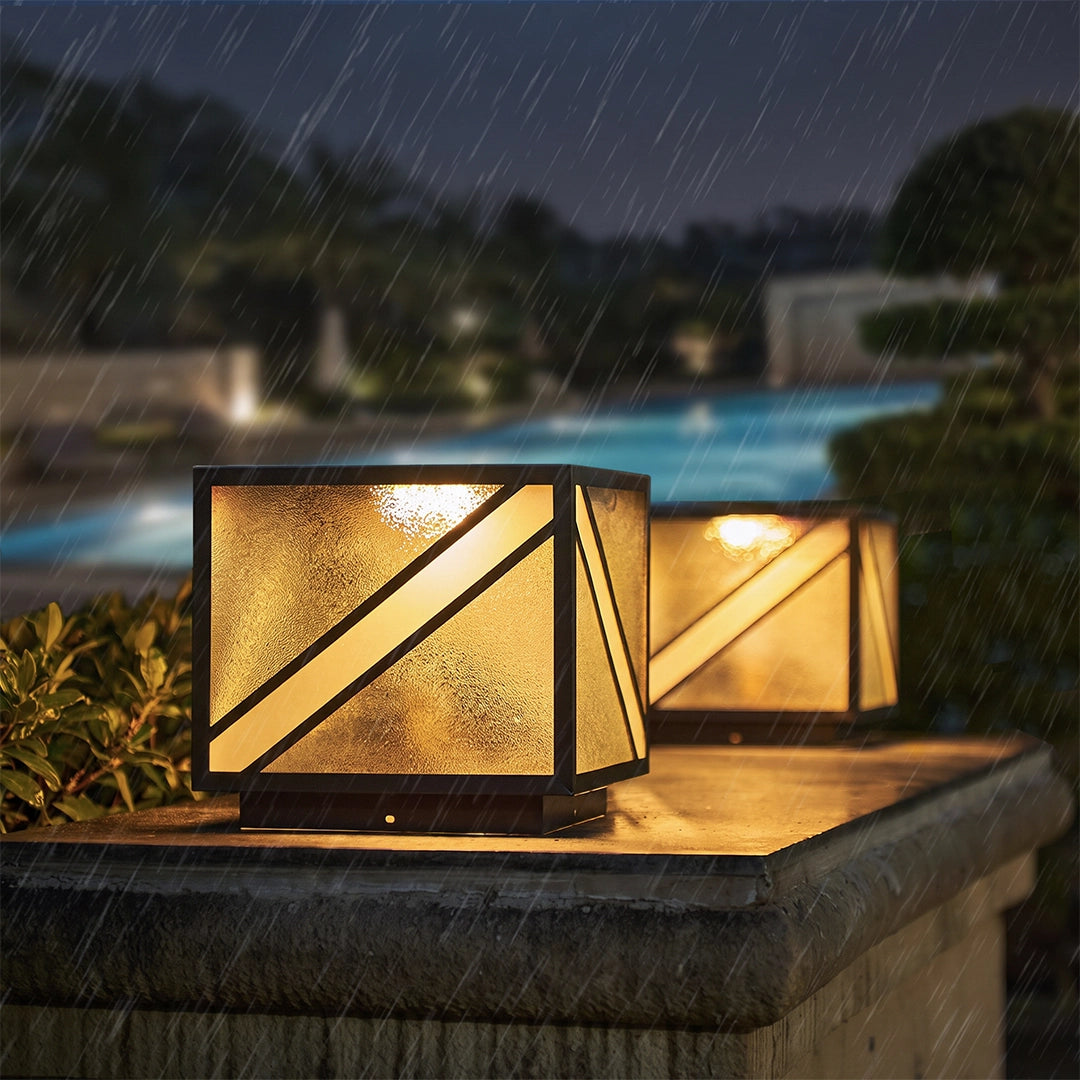 Modern solar pillar lights with warm glow beside swimming pool in the rain