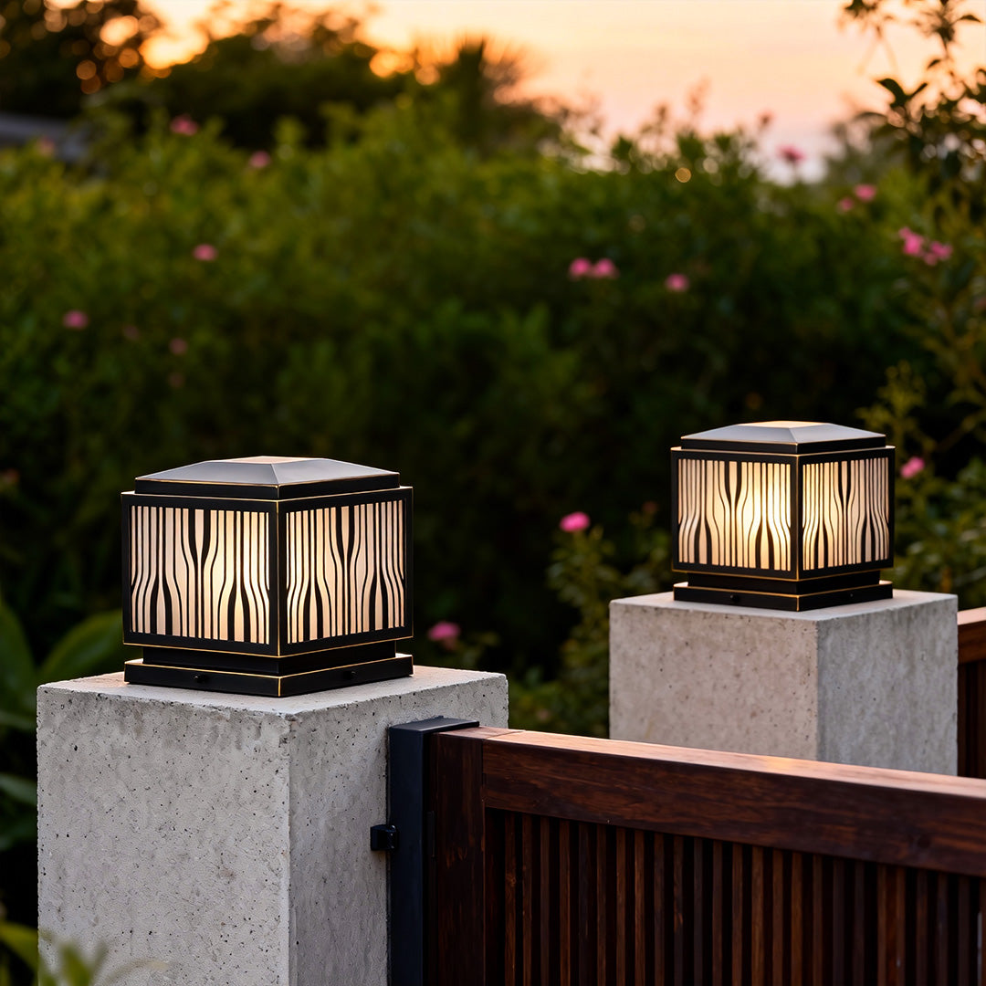 Modern solar pillar lights illuminating a stone pillar beside a wooden fence at dusk.
