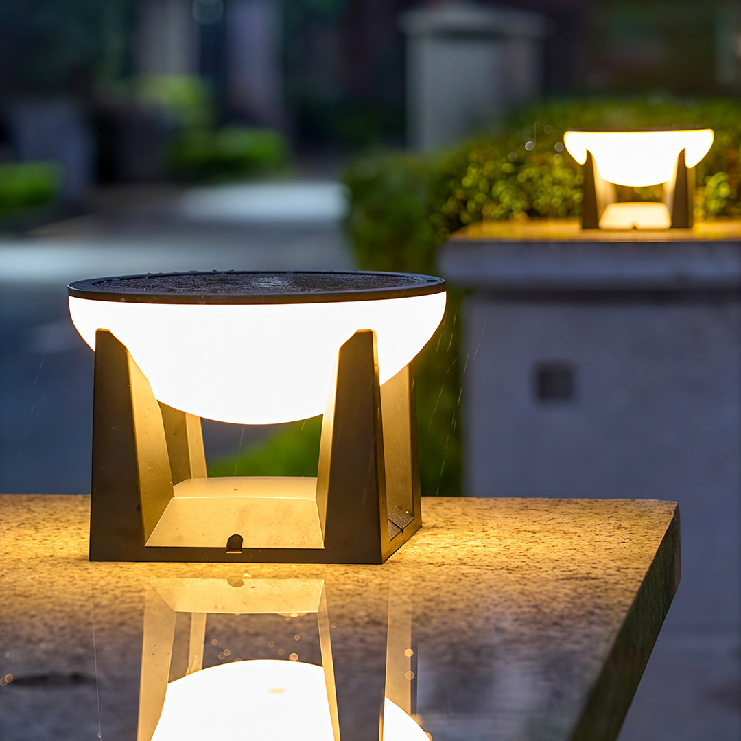 Modern solar powered bollard light casting a warm glow and reflecting on a wet granite surface.
