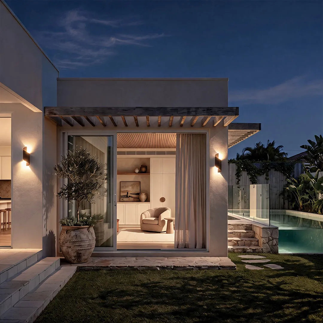 Modern spiral wall light installed beside a contemporary outdoor patio, casting warm ambient light on the exterior wall at night.
