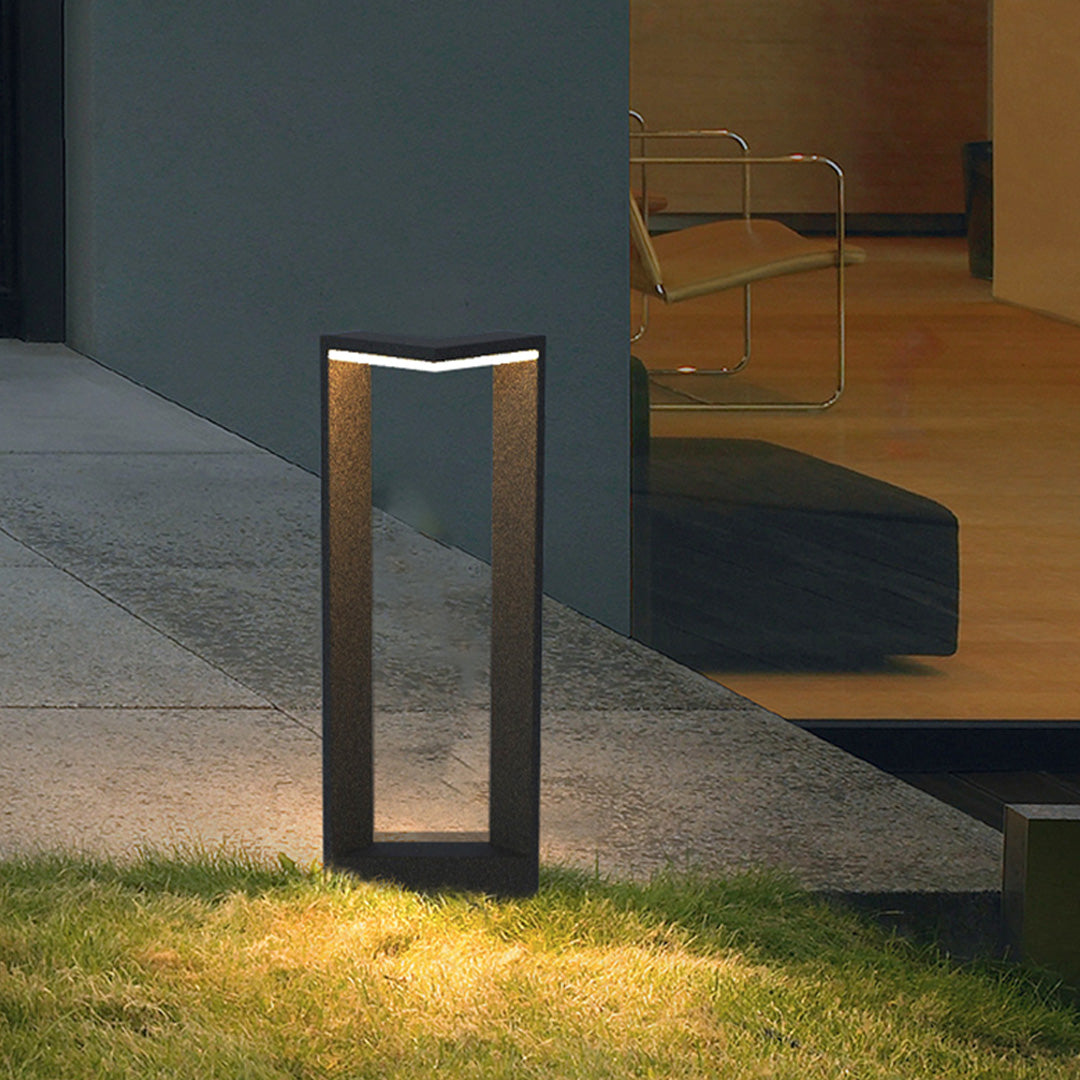 Modern square bollard light illuminating an outdoor pathway with a sleek rectangular frame.