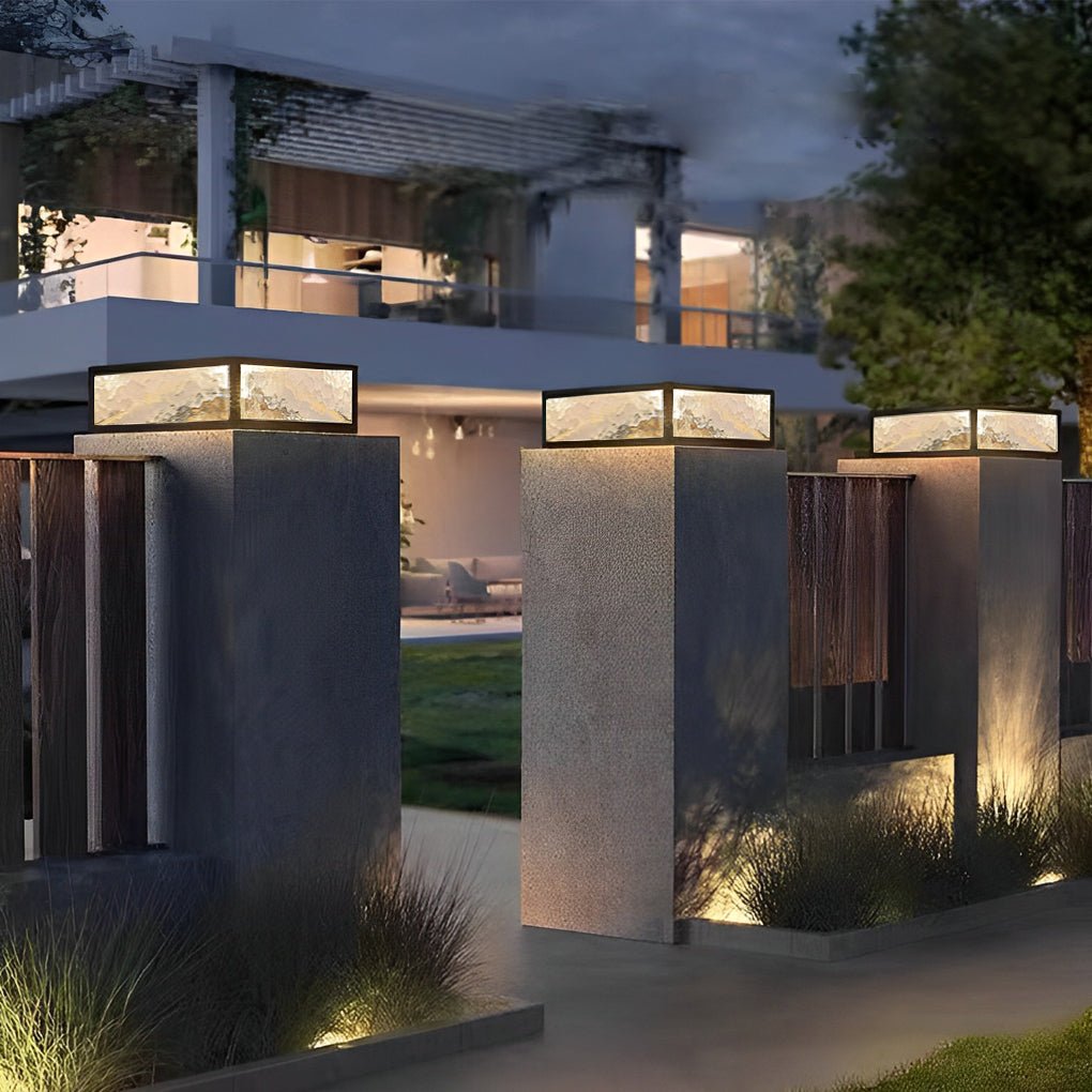 Modern square outdoor pillar lights installed on concrete columns in a contemporary courtyard.