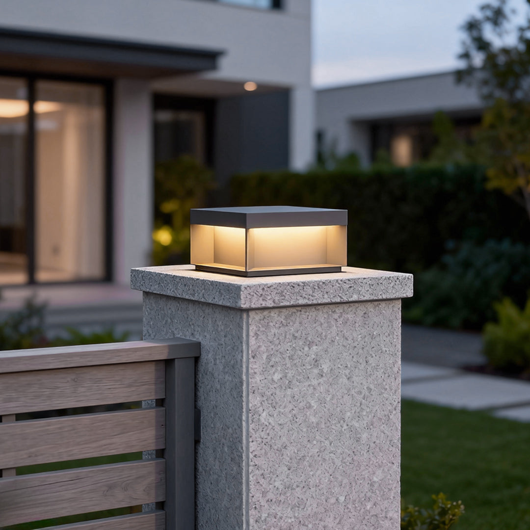 Modern square solar deck light mounted on stone pillar at residential entrance.