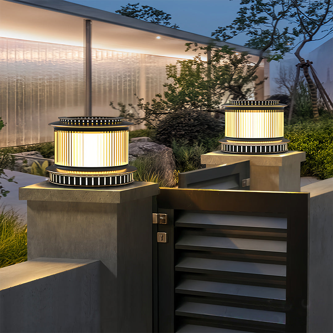 Stainless steel pillar lights placed by a modern entrance gate, providing bright illumination for outdoor spaces.