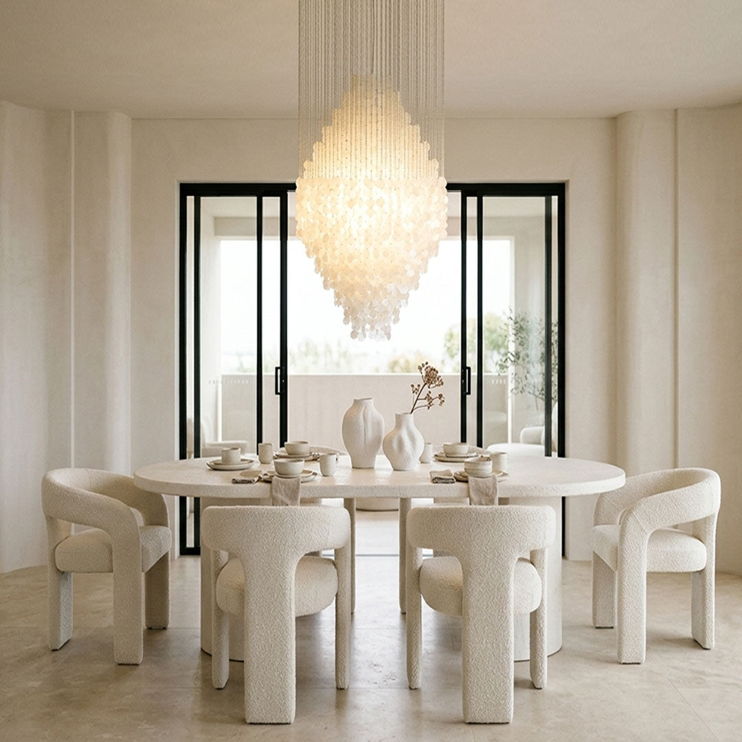 Modern staircase chandelier hanging above a dining area with elegant cascading crystal layers.