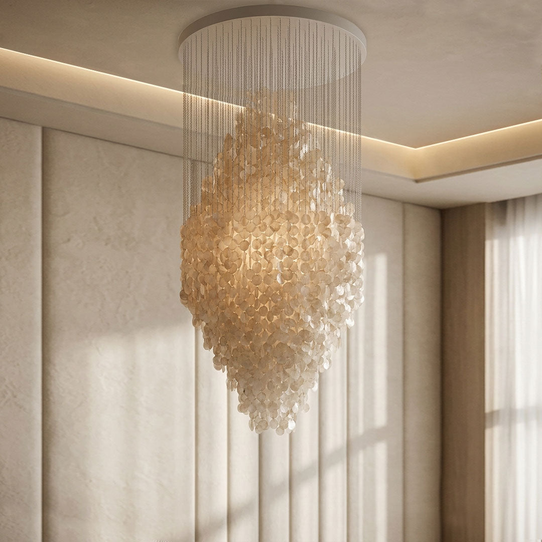 Modern staircase chandelier installed in a double-height interior with warm decorative illumination.