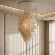 Modern staircase chandelier installed in a double-height interior with warm decorative illumination.