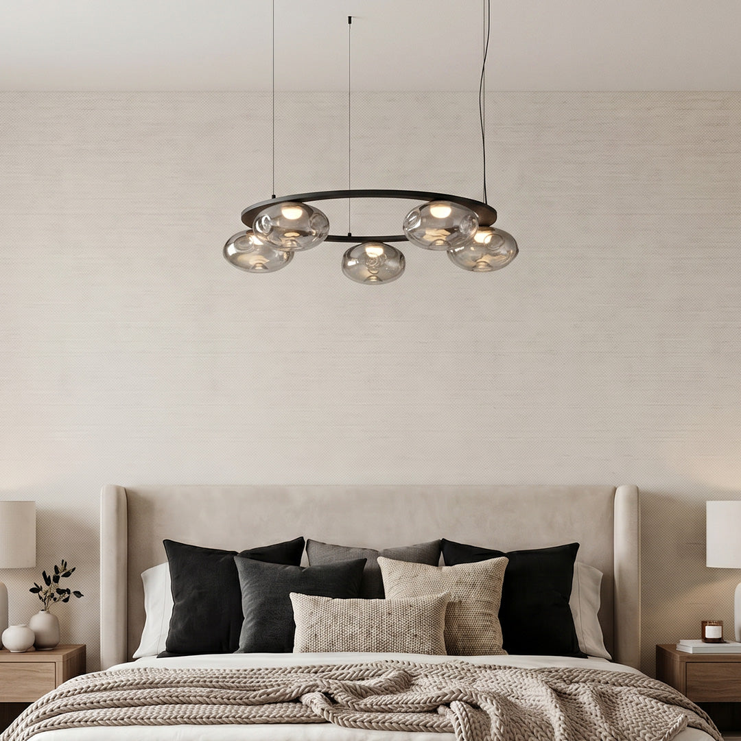 Modern traditional chandelier above a bed in a warm neutral bedroom setting.