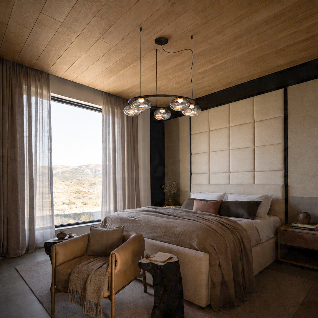 Modern traditional chandelier installed in a cozy bedroom with wood ceiling.