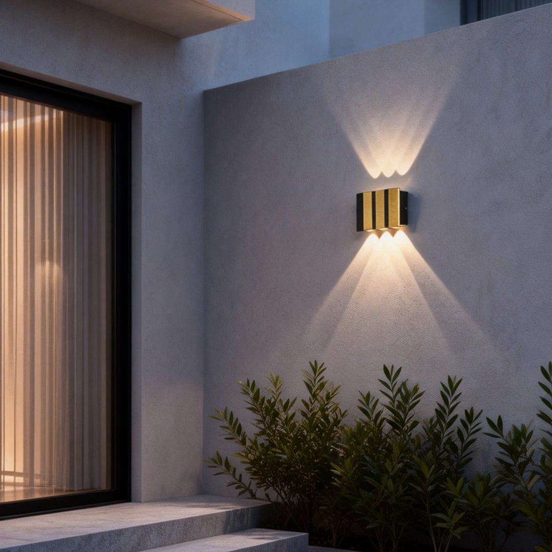 Modern up and down wall lights installed beside a minimalist outdoor lounge, highlighting architectural lines with soft ambient lighting.