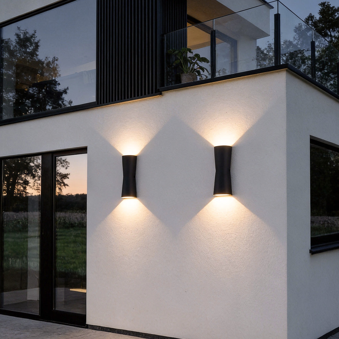 Modern up and down exterior wall lights installed on a minimalist residential facade at dusk.
