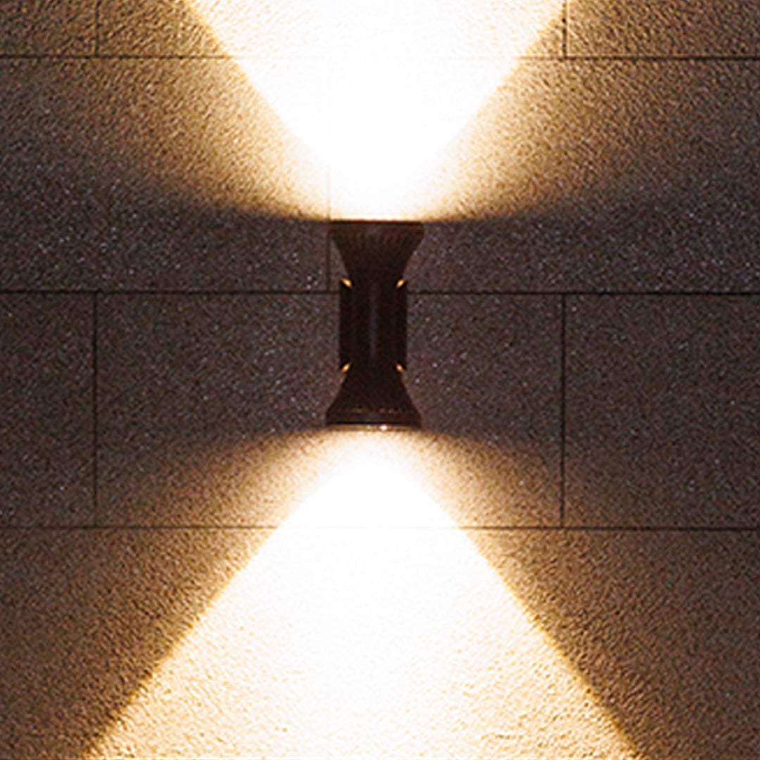 Warm golden light from a modern up-down Outdoor Wall Lighting Fixture creating an hourglass pattern on a smooth exterior wall.
