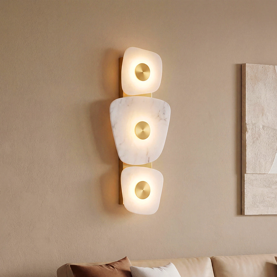 Luxury vertical wall art lighted featuring organic marble stones and gold accents on beige wall.