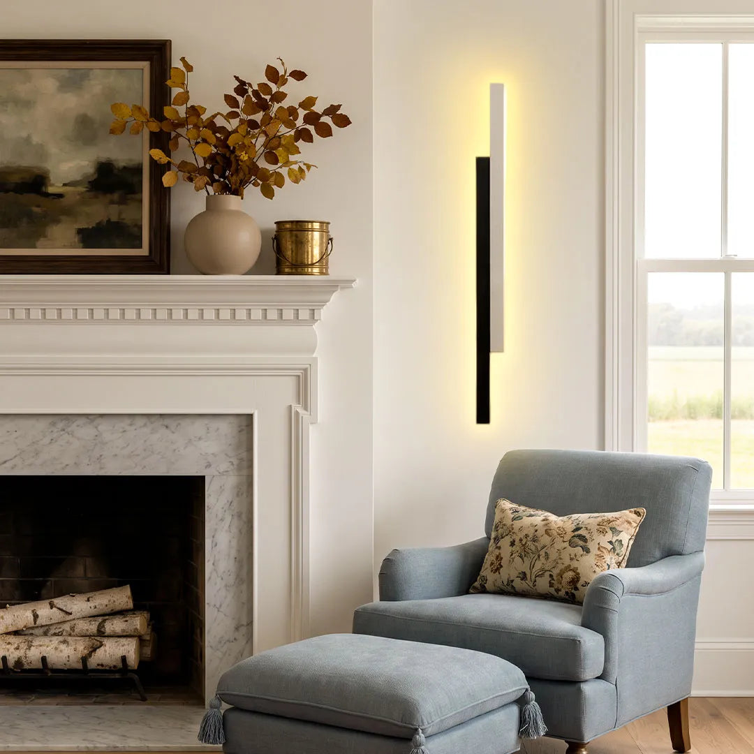 Modern vertical wall light mounted beside a fireplace and blue accent chair in a cozy living room.
