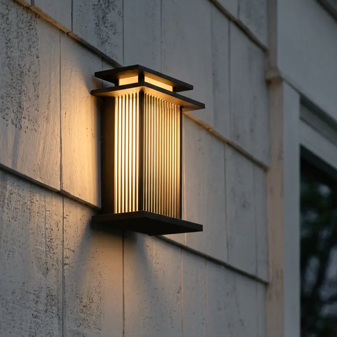 Modern vertical wall sconce mounted on a light-colored exterior wall in a close-up angled view.