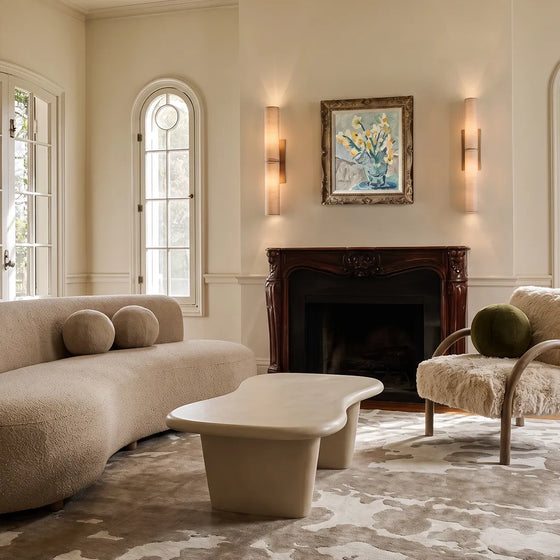 Modern vertical wall sconce lighting a fireplace wall in a bright contemporary living room.