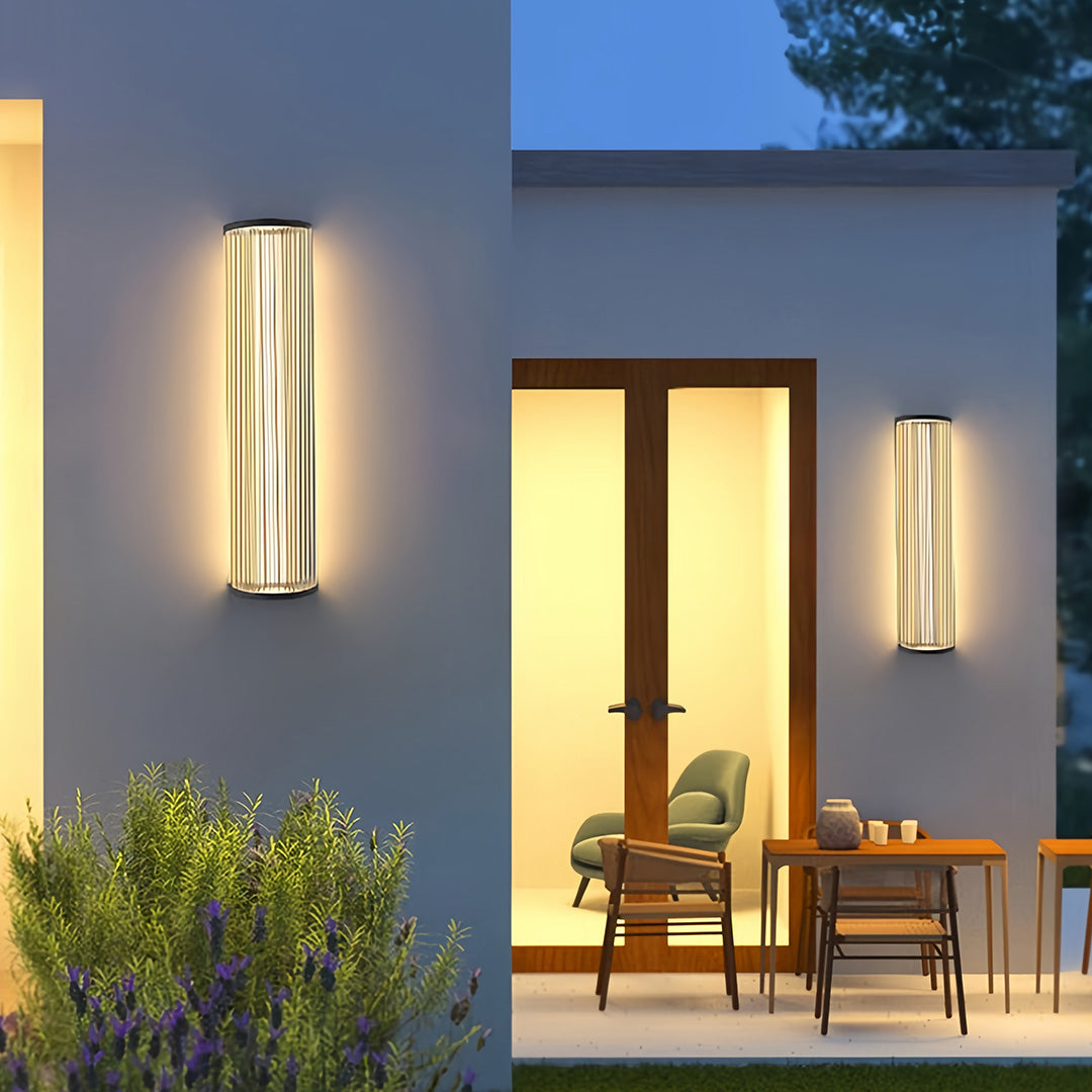 Modern vertical wall sconce lighting illuminating the exterior of a contemporary home and patio area at dusk.