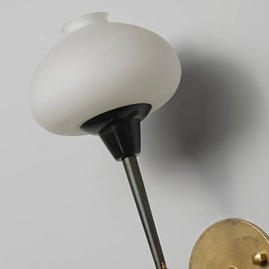 Modern wall light fixture close-up showing the frosted glass shade and dark metal stem.
