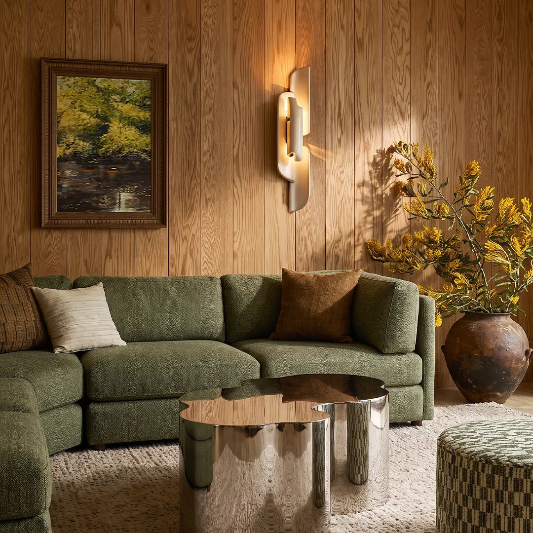 Modern wall light fixtures adding warm accent lighting above a green sofa in a contemporary room.