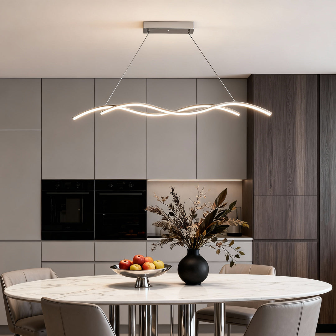 Modern wave LED pendant light installed over a marble dining table in a minimalist interior setting.