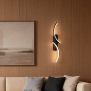 Modern wave wall sconce illuminating a cozy living room with warm, elegant glow.