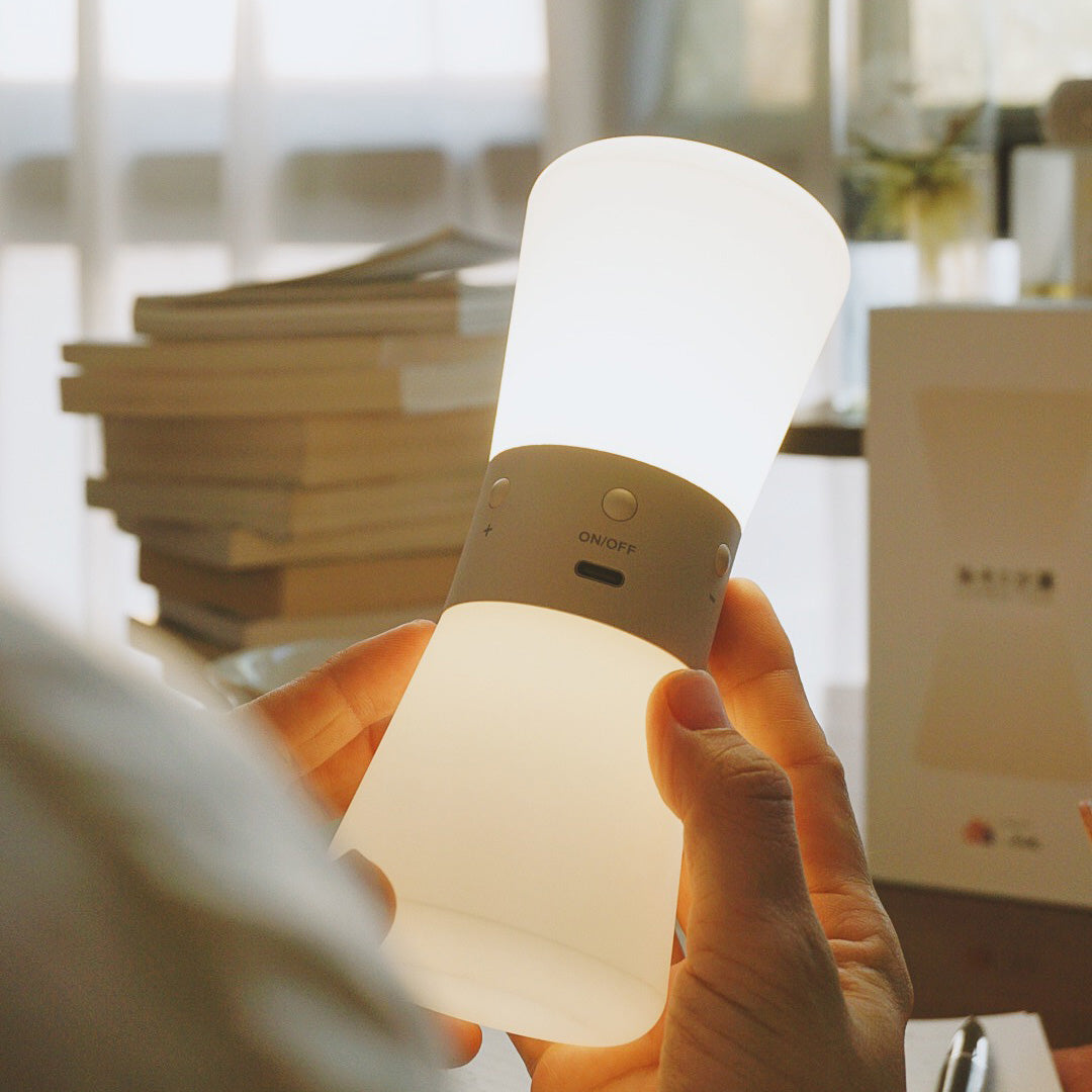 Modern white USB rechargeable table lamp illuminating bedside reading area with books