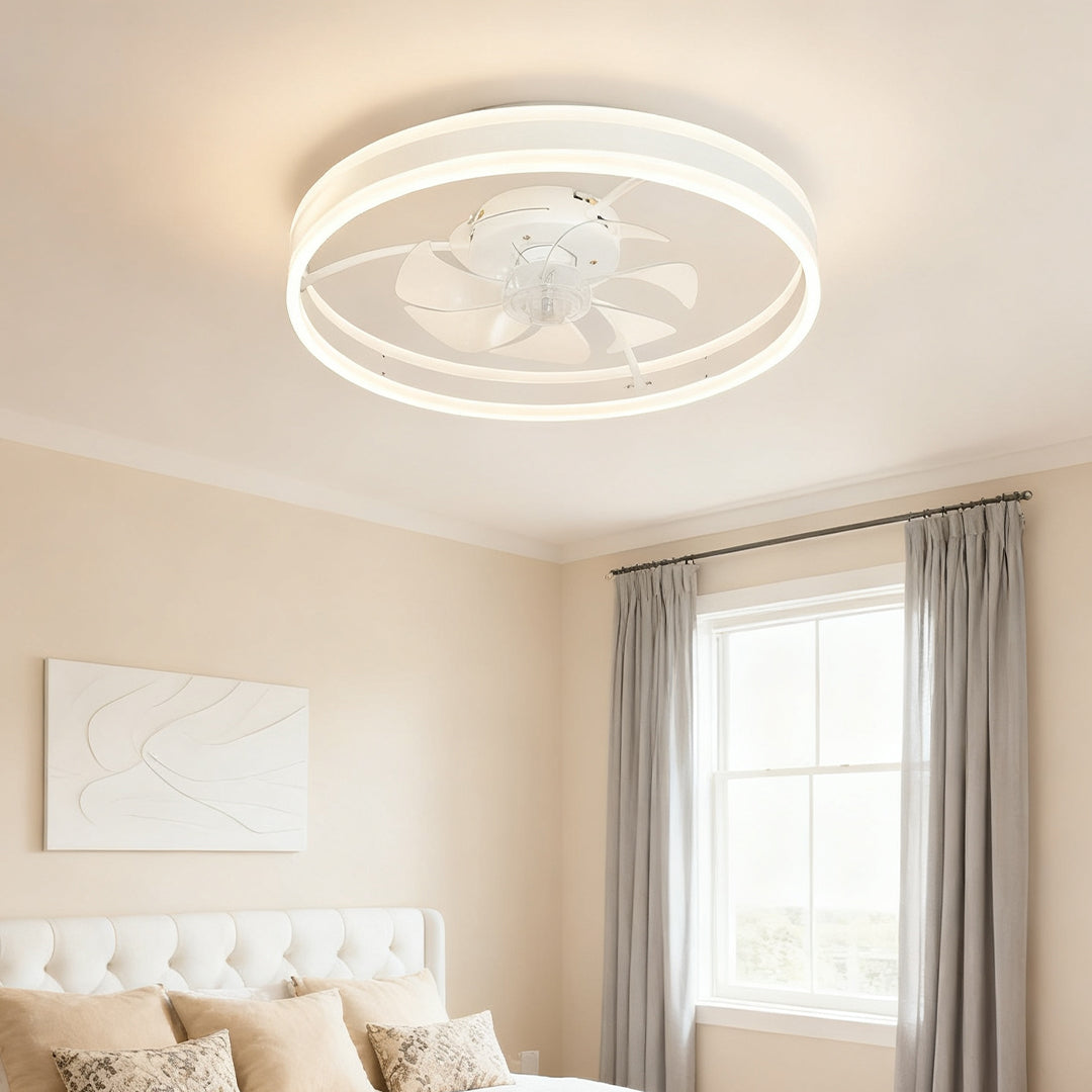 Modern white ceiling fan with light illuminating a neutrally decorated bedroom with soft beige walls and simple decor. 