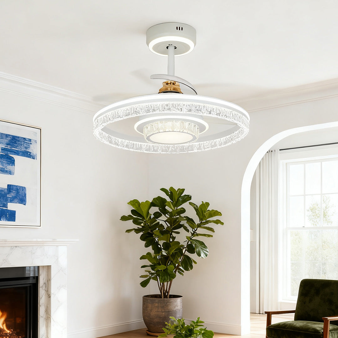 Modern white ceiling fan with round light and crystal ring, installed in a chic living room setting above a lush houseplant. 