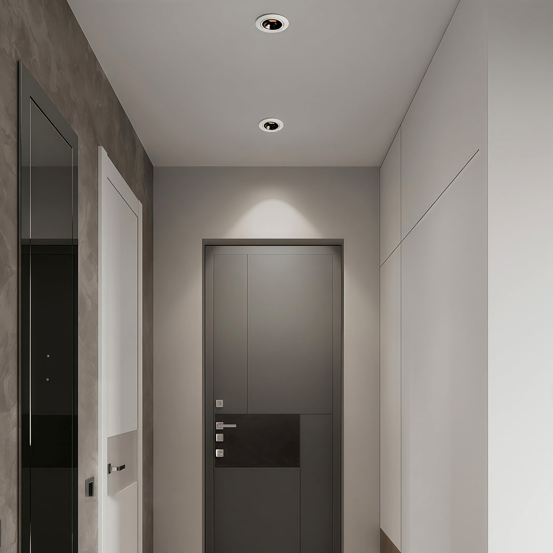 Modern white entryway illuminated by sleek directional recessed downlight fixtures highlighting the doorway.