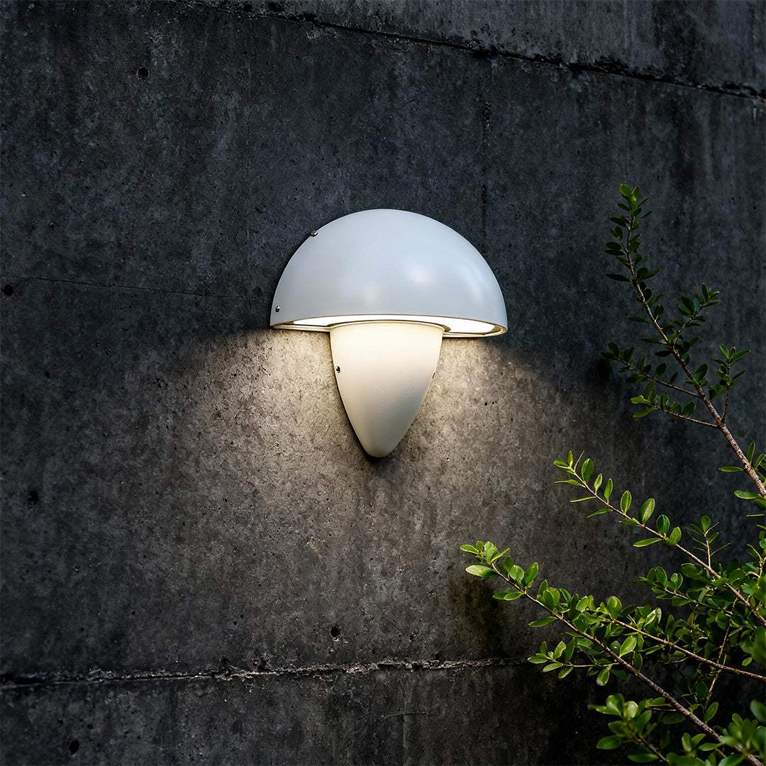 White mushroom wall light with a modern design, mounted on an exterior wall, creating a bright and inviting outdoor space.