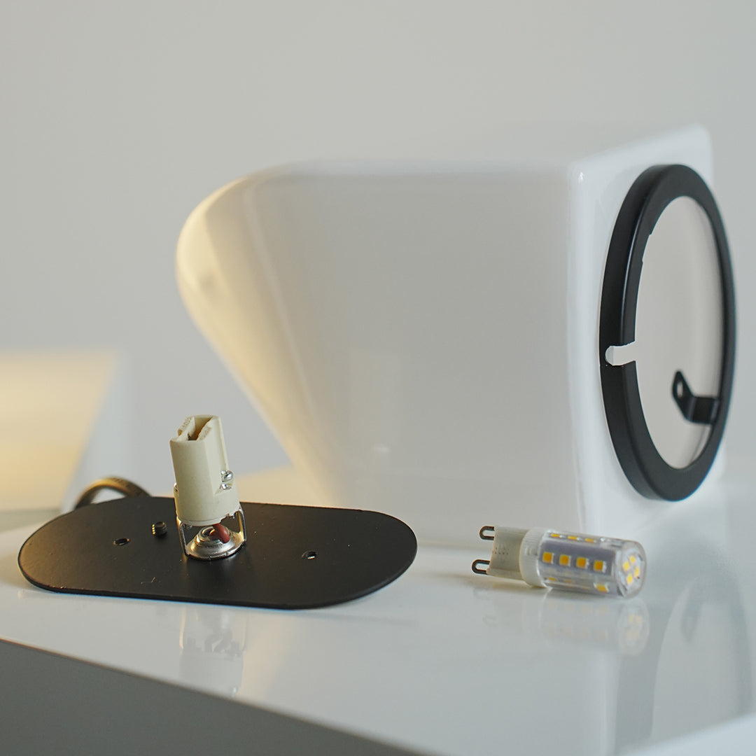 Modern white table lamp with plug base and light module detail.