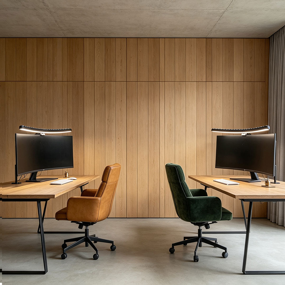 Monitor LED light bars mounted above two computer screens in a minimalist wood-paneled office.