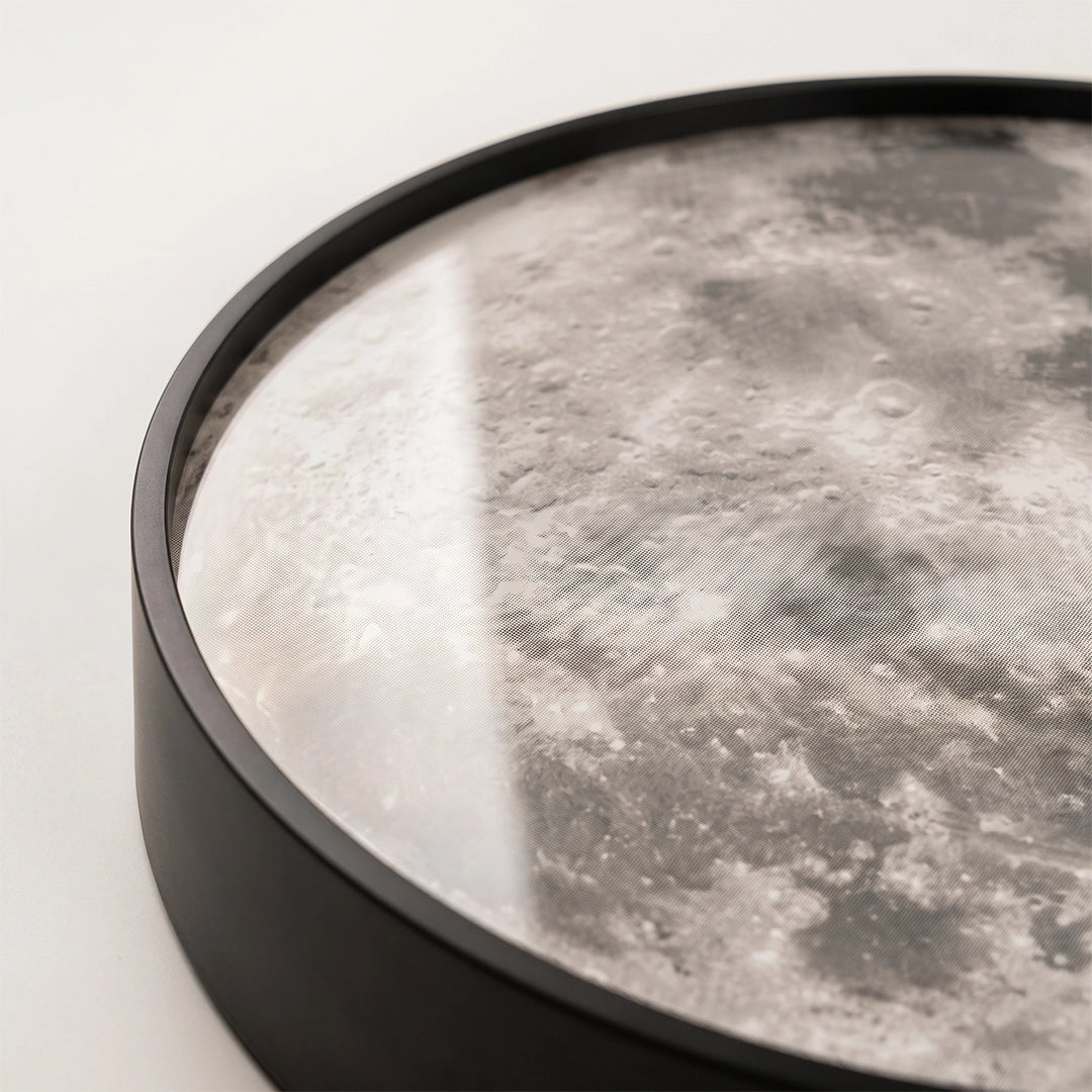 Close-up of the black round frame and moon-patterned diffuser on a moon ceiling light.
