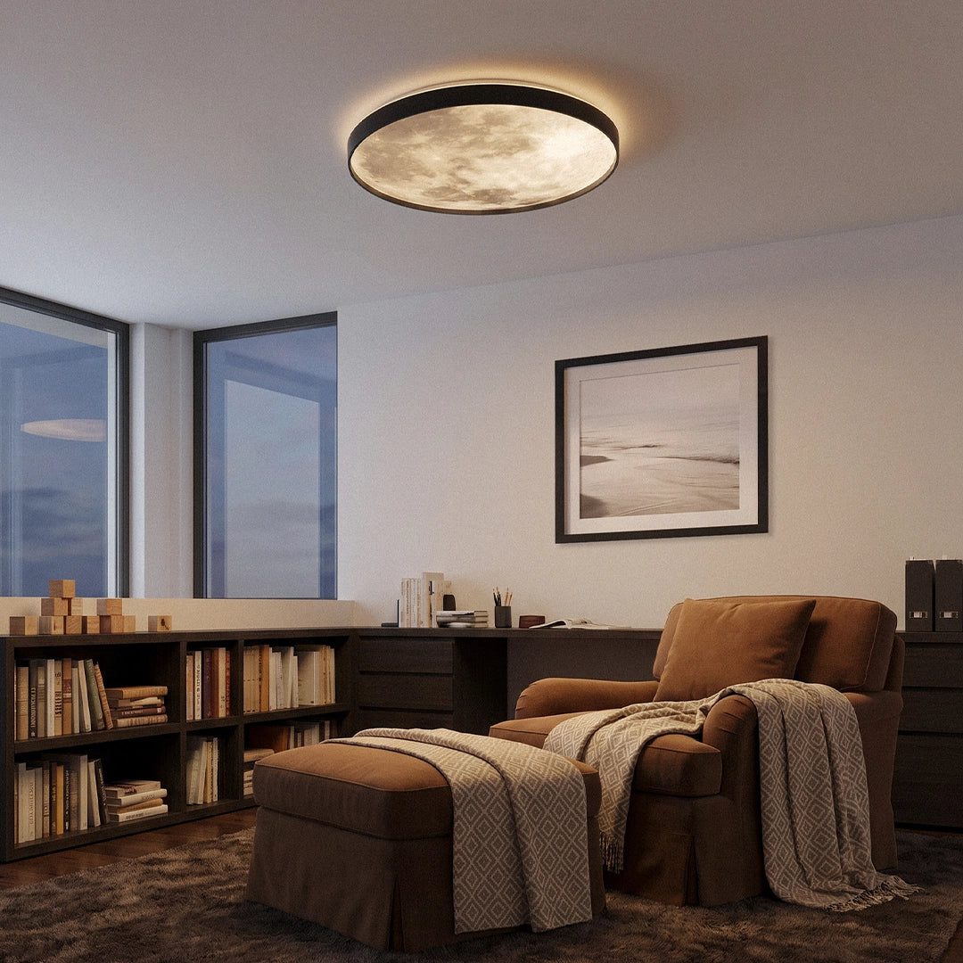 Moon ceiling light mounted on the ceiling of a reading room with a chair, bookshelves, and framed wall art.