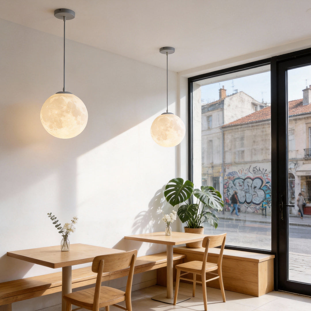 Moon globe pendant light installed over cafe dining table with warm ambient glow.