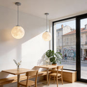 Moon globe pendant light installed over cafe dining table with warm ambient glow.