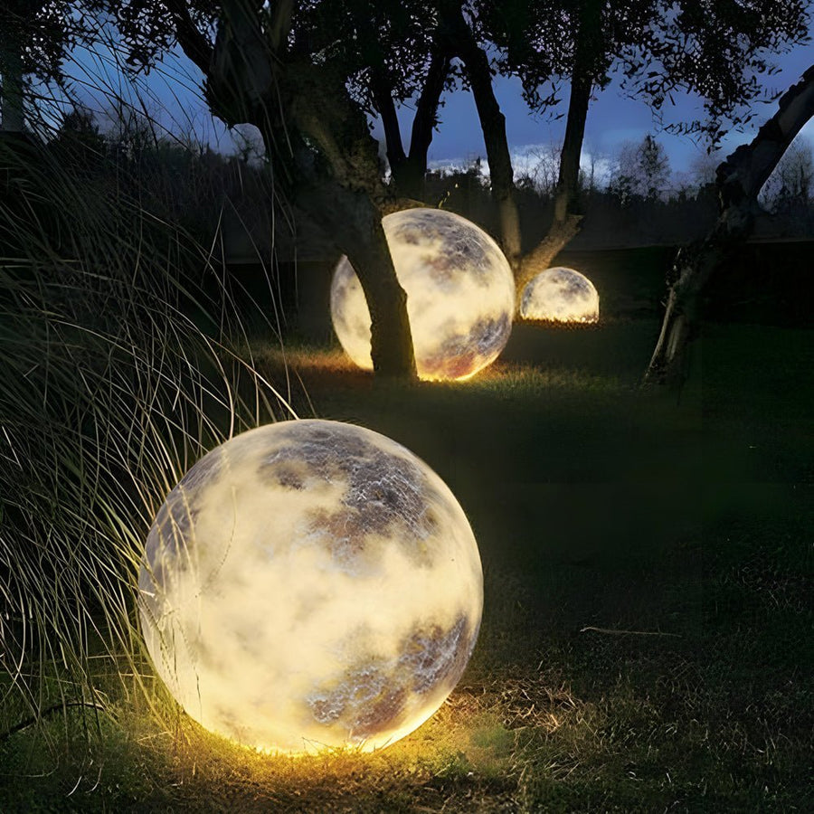 Moon light sphere placed under trees in a nighttime garden