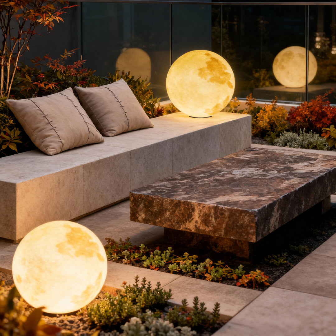 Moon-shaped stone pillar light beside modern outdoor sofa and stone bench in cozy garden.