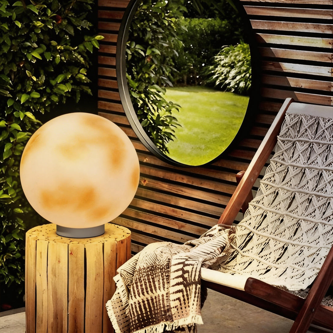 Modern moon-shaped stone pillar light glowing on a rustic wood stump in a cozy outdoor patio ok.